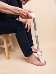 Man using a white long handled nail filing on a beige background