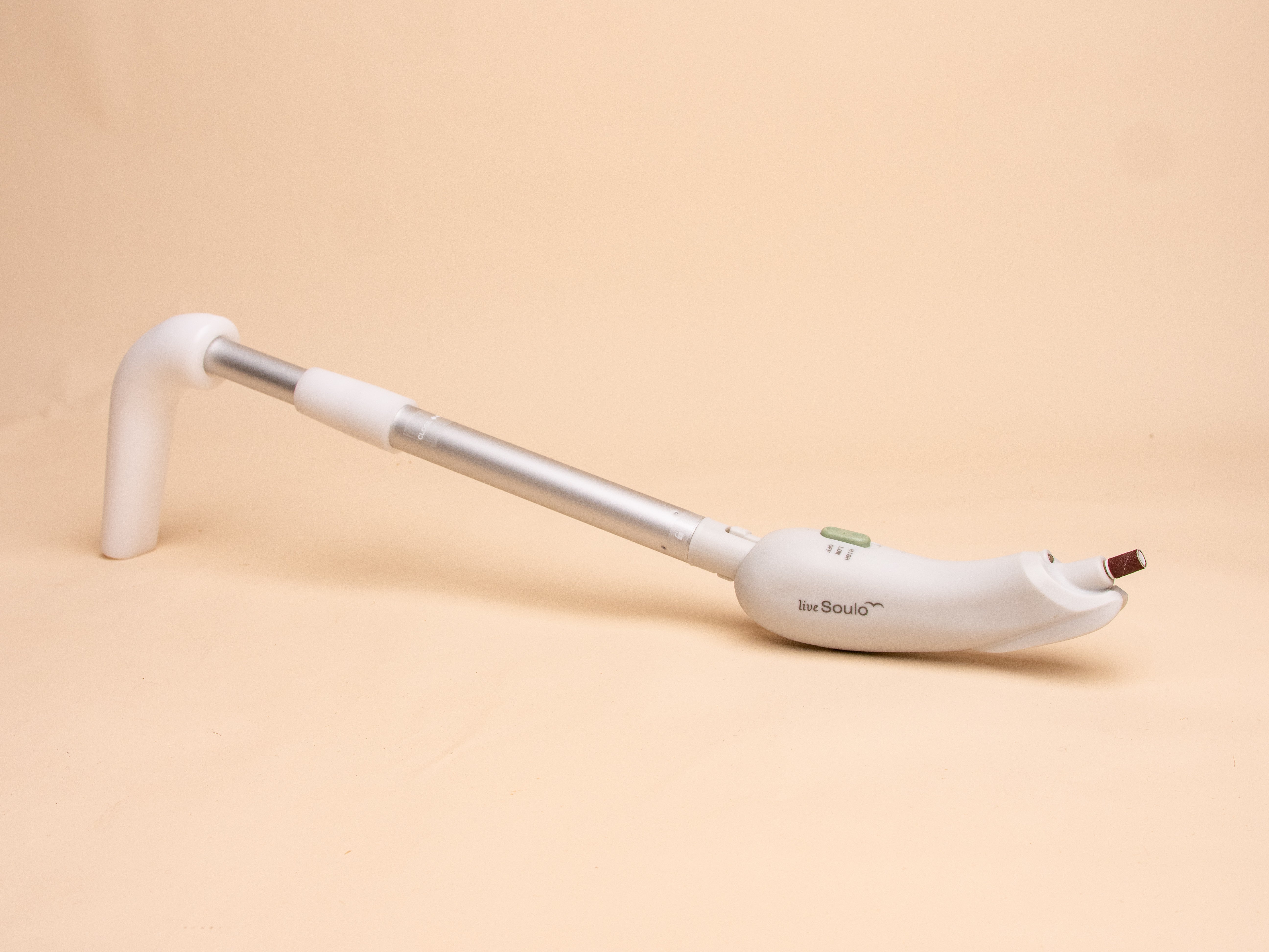 White long handled nail filing device on a beige background